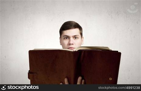Reading book. Young man with opened book in hands