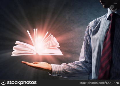 Reading books concept. Close up of hand holding in palm glowing book