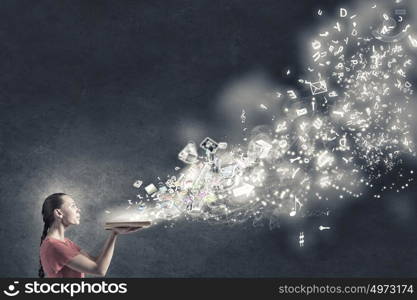 Reading books. Young girl with book in hands blowing letters from pages