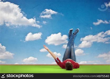 Reading develope imagination. Young man lying on floor with legs raised up