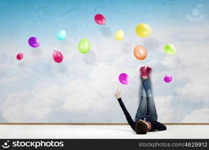 Reading develope imagination. Young woman lying on floor with legs raised up