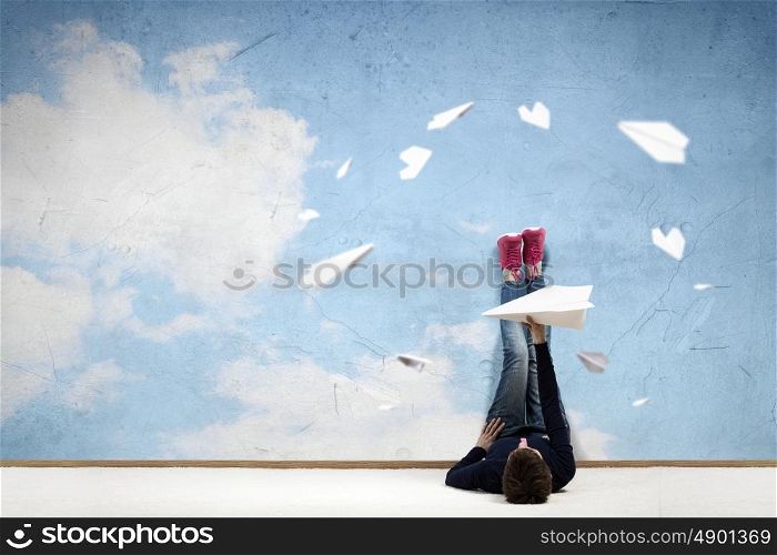 Reading develope imagination. Young woman lying on floor with legs raised up