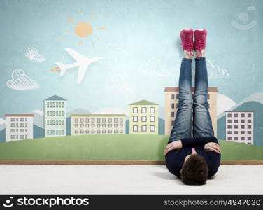 Reading develope imagination. Young woman lying on floor with legs raised up