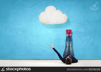 Reading develope imagination. Young woman lying on floor with legs raised up