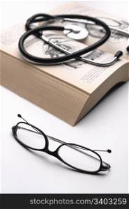 Reading glasses and phonendoscope on a anatomy guide
