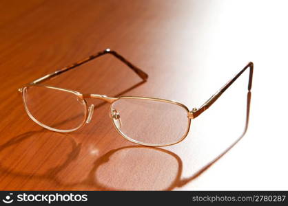 Reading glasses on the wooden background