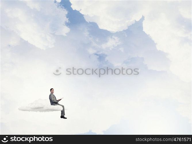 Reading in isolation. Young businessman floating on cloud with book in hands