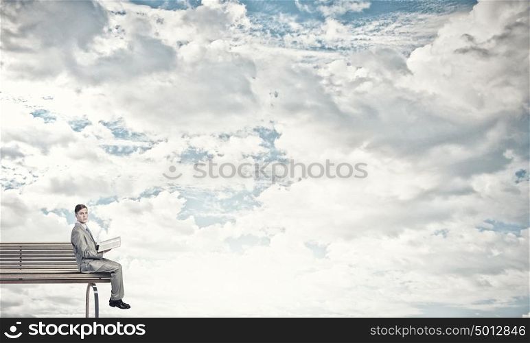 Reading in isolation. Young businessman sitting on bench with book in hands