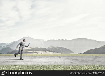 Reading on the run. Young businessman running with book in hand