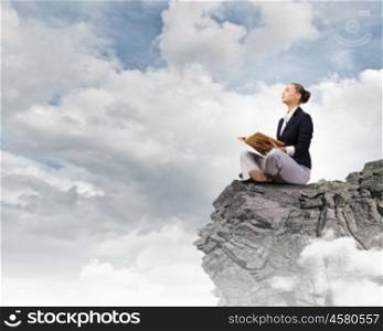 Reading woman. Young attractive woman sitting on top of building and reading book