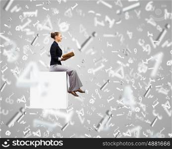 Reading woman. Young attractive woman sitting on white cube and reading book
