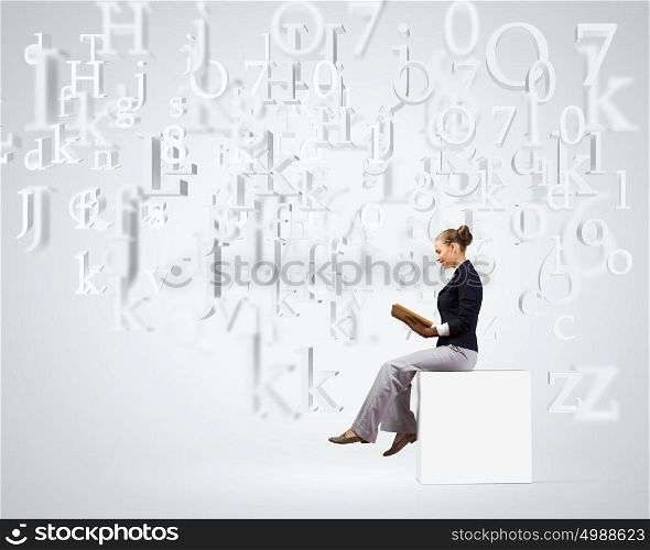 Reading woman. Young attractive woman sitting on white cube and reading book