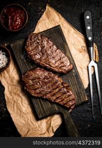 Ready steak grill on a cutting board. On a black background. High quality photo. Ready steak grill on a cutting board.