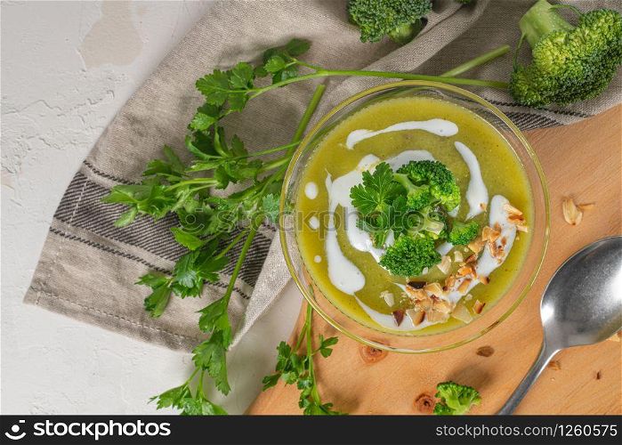 Ready to eat fresh hot broccoli puree soup with pieces of broccoli and parsley leaves in a bowl on a wooden table. Close-up. Healthy eating and lifestyle. Top view