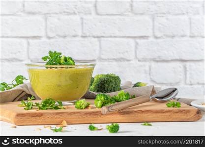 Ready to eat fresh hot broccoli puree soup with pieces of broccoli and basil leaves in a wooden plate on a wooden table. Close-up. Healthy eating and lifestyle.
