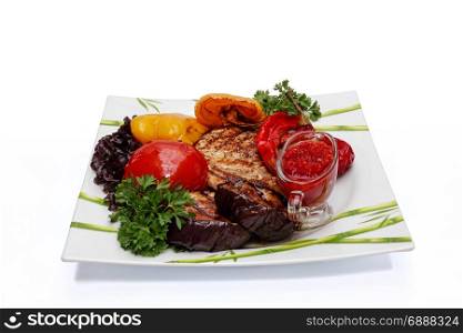 Ready-to-eat steak with baked vegetables. Prepared beef steak with vegetable decoration, close-up on a white background.