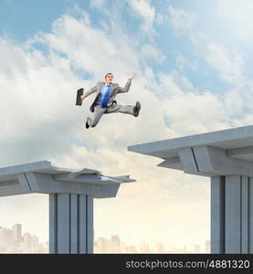 Ready to take a risk. Businessman jumping over a gap in the bridge as a symbol of bridge