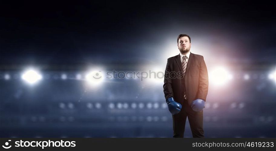 Ready to take the challenge. Businessman in suit and boxing gloves at sport arena