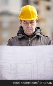 real builder with blueprints on construction site, natural light, focus on face