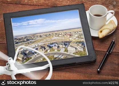real estate aerial photography concept - reviewing pictures of of new house development on a tablet with a drone and coffee, screen image copyright by the photographer