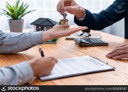 Real estate agent handing house key to buyer after signing rental least contract during house loan meeting. Successful property sale purchase agreement for new home ownership. Entity. Real estate agent handing house key to buyer. Entity
