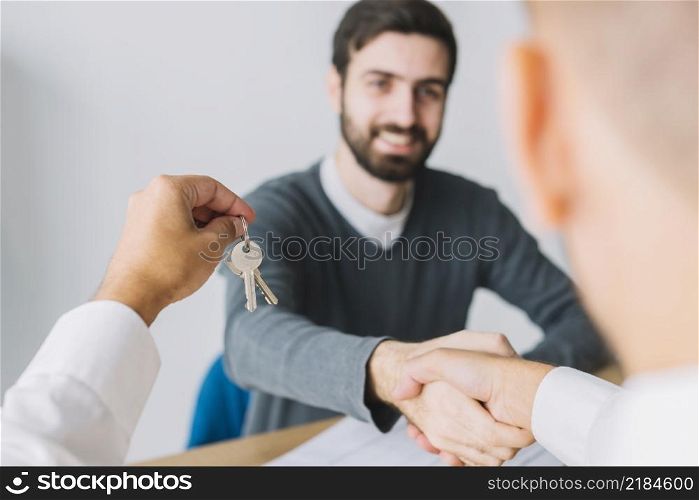 real estate agent shaking hand client holding keys