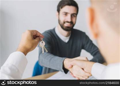 real estate agent shaking hand client holding keys