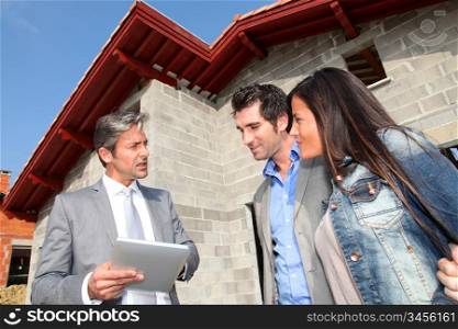 Real-estate agent showing house under construction to couple