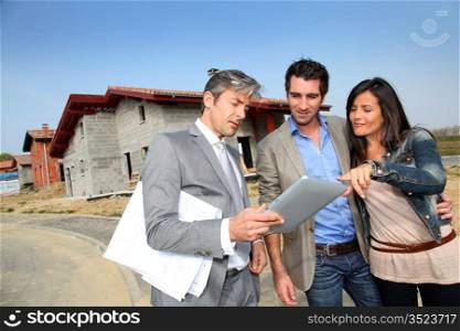 Real-estate agent showing house under construction to couple