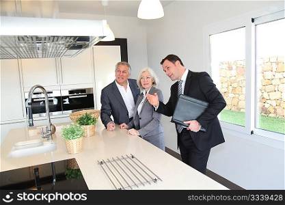 Real-estate agent showing interior of house to senior couple