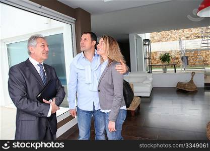 Real estate agent showing modern house to couple