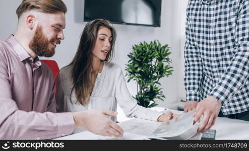 Real-estate agent shows a build project to a young couple. . Real-Estate Agent Showing a Build Project to a Young Couple