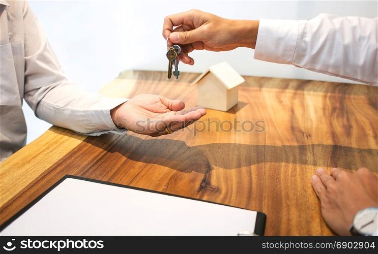 Real Estate agent with customer making contract signature giving a key buy / rent a house