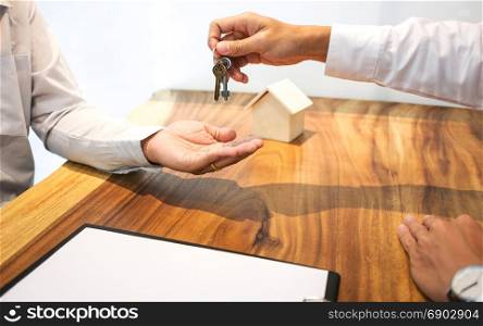 Real Estate agent with customer making contract signature giving a key buy / rent a house