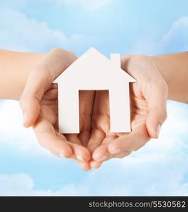 real estate and accomodation concept - closeup picture of female hands holding paper house