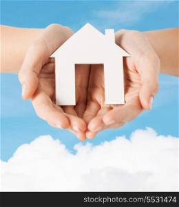 real estate and accomodation concept - closeup picture of female hands holding paper house