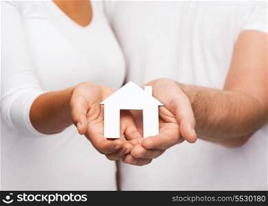real estate and family concept - closeup of couple hands holding paper house