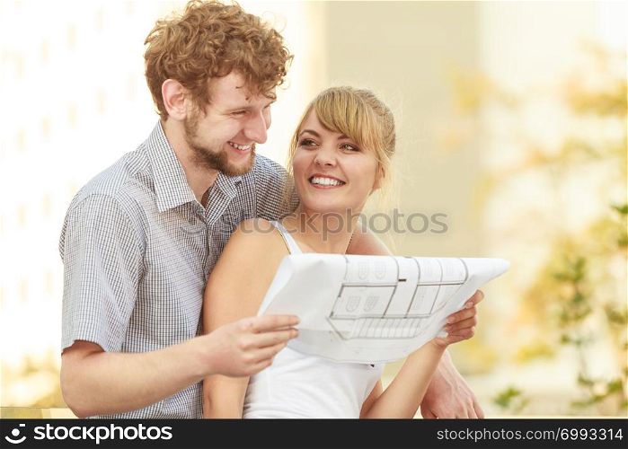 Real estate and family concept - young couple with blueprint project building plans dreaming about new house in modern residential area. couple with blueprint project building plans outdoor