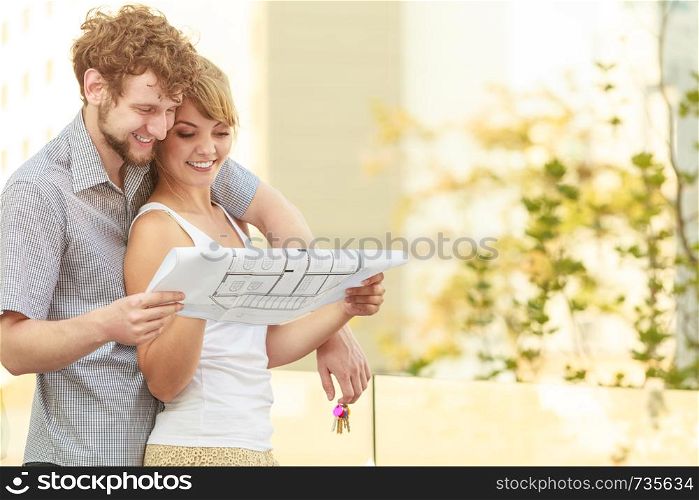 Real estate and family concept - young couple with blueprint project building plans and keys dreaming about new house in modern residential area. couple with blueprint project keys outdoor
