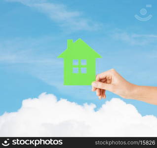 real estate and family home concept - closeup picture of female hand holding green paper house