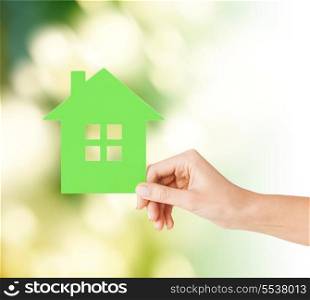 real estate and family home concept - closeup picture of female hand holding green paper house
