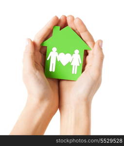 real estate and family home concept - closeup picture of female hands holding green paper house with family