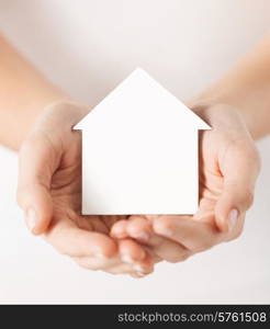 real estate and family home concept - closeup picture of female hands holding white blank paper house
