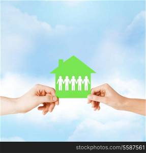 real estate and family home concept - isolated closeup picture of male and female hands holding green paper house