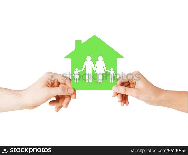 real estate and family home concept - isolated picture of male and female hands holding green paper house with family