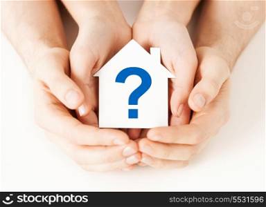 real estate and family home concept - male and female hands holding paper house with question mark