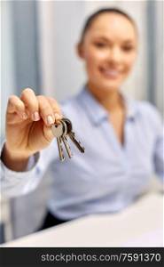 real estate business and people concept - close up of businesswoman or realtor holding keys at office. businesswoman or realtor holding keys at office