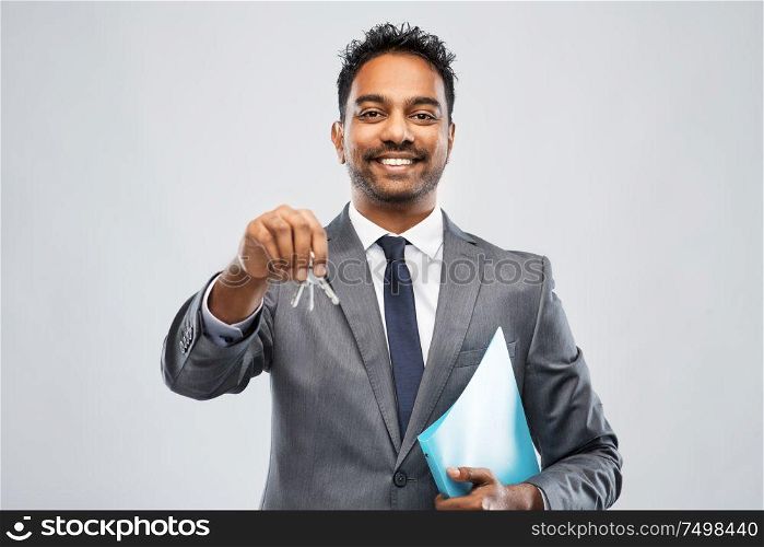 real estate business and people concept - indian man realtor with key and folder over grey background. indian man realtor with key and folder