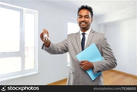 real estate business and people concept - indian man realtor with key and folder over empty new apartment room background. indian man realtor with key and folder at new home