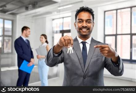 real estate business and people concept - indian man realtor with keys and clients over empty office room background. indian man realtor with keys at empty office room